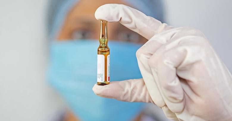 Indian scientist holding a vaccine ampoule